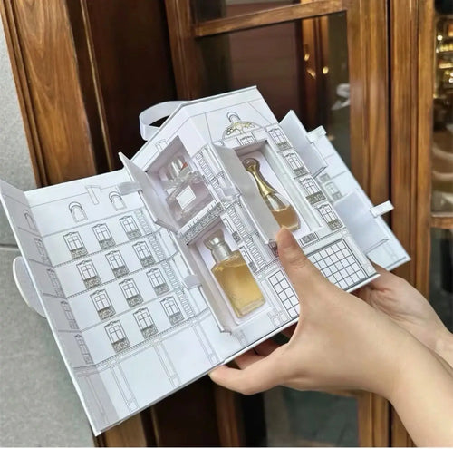 "Open white gift box featuring five mini perfume bottles, with a detailed illustration of a building on the inside."