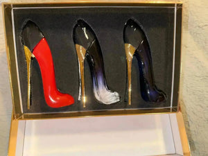 "Three stiletto perfume bottles in a black and gold display case: red, black ombre, and dark blue with gold accents."