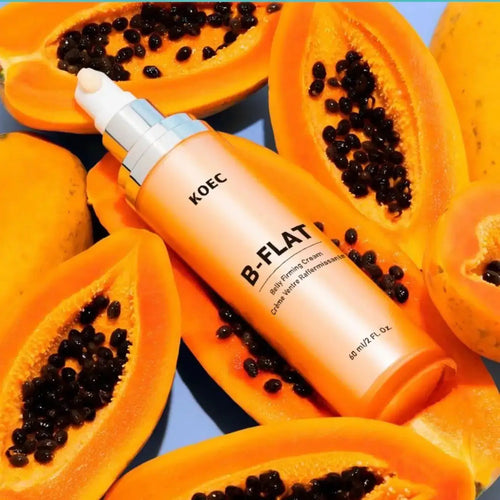 "KOEC B-FLAT Belly Firming Cream in a pump bottle, surrounded by bright orange papaya halves on a blue background."