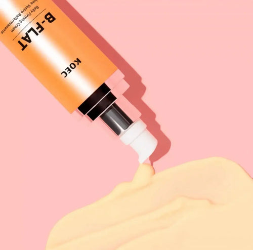 "KOEC B-FLAT Belly Firming Cream tube in orange and black, with cream oozing from the nozzle on a pink background."