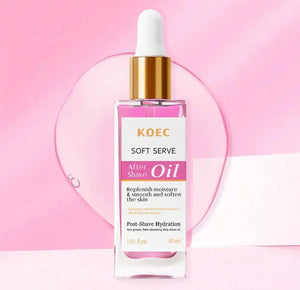 Clear glass bottle with a gold dropper cap, filled with pink oil, labeled "KOEC Soft Serve After Shave Oil," set against a pi