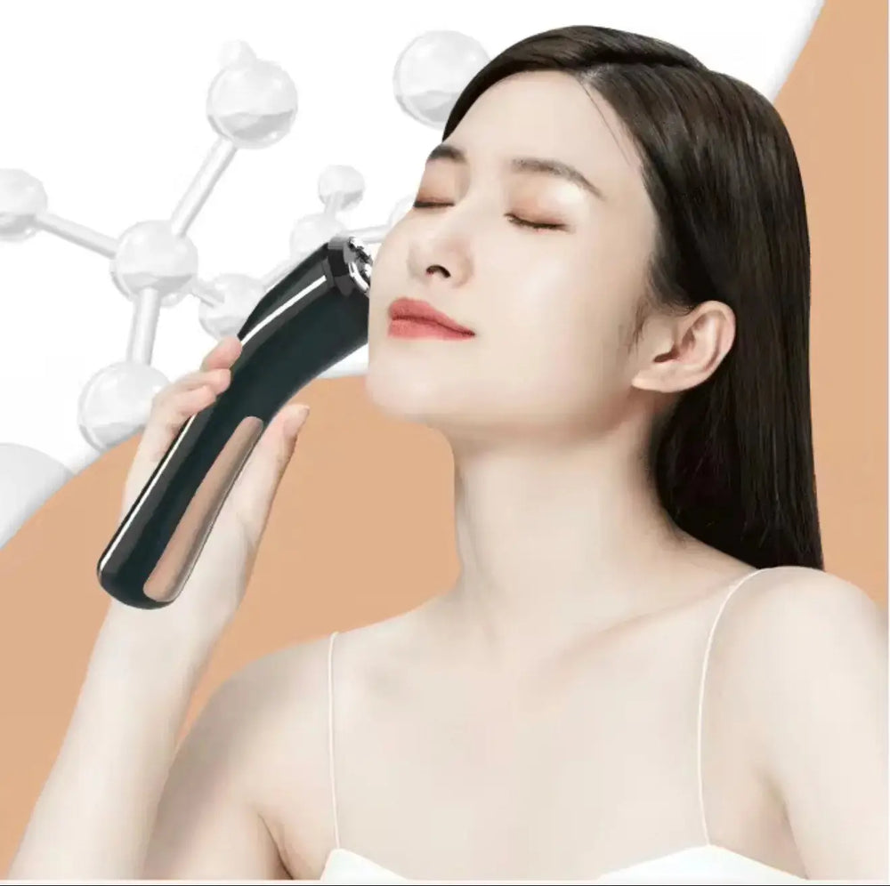 "Black 3-in-1 microcurrent facial device held against a woman's cheek with a smooth, minimalist design, on a peach background