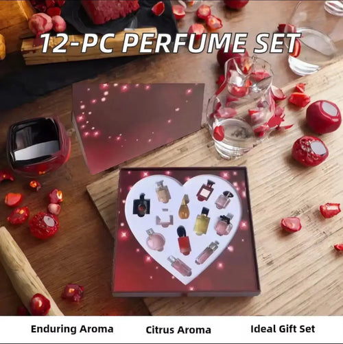 "12 mini perfume bottles in heart-shaped arrangement, displayed in a dark box with red accents and floral decorations."