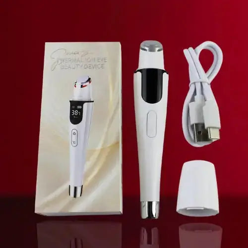 "White Thermal Ion Eye Massager with silver accents, display screen, and USB charging cable, next to packaging on red backgro
