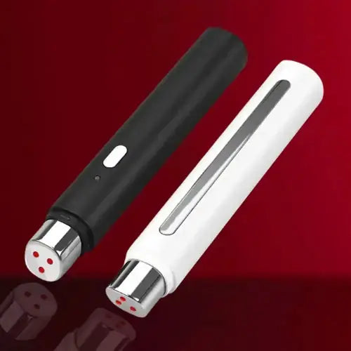 "Black and white heated eye massager pen with metallic accents and red indicator lights, resting on a reflective surface."