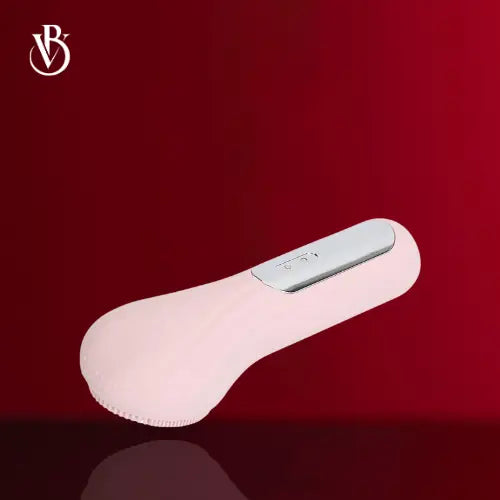 "Pink waterproof sonic facial cleansing brush with a silver button and textured silicone head, angled view"