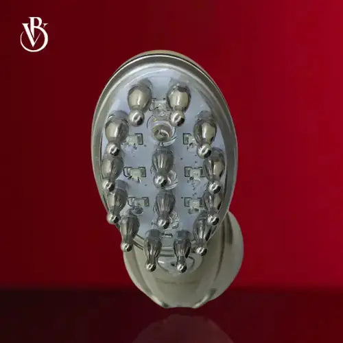 "White rechargeable electric scalp massager with silver massage nodes, oval shape, viewed from above against a red background